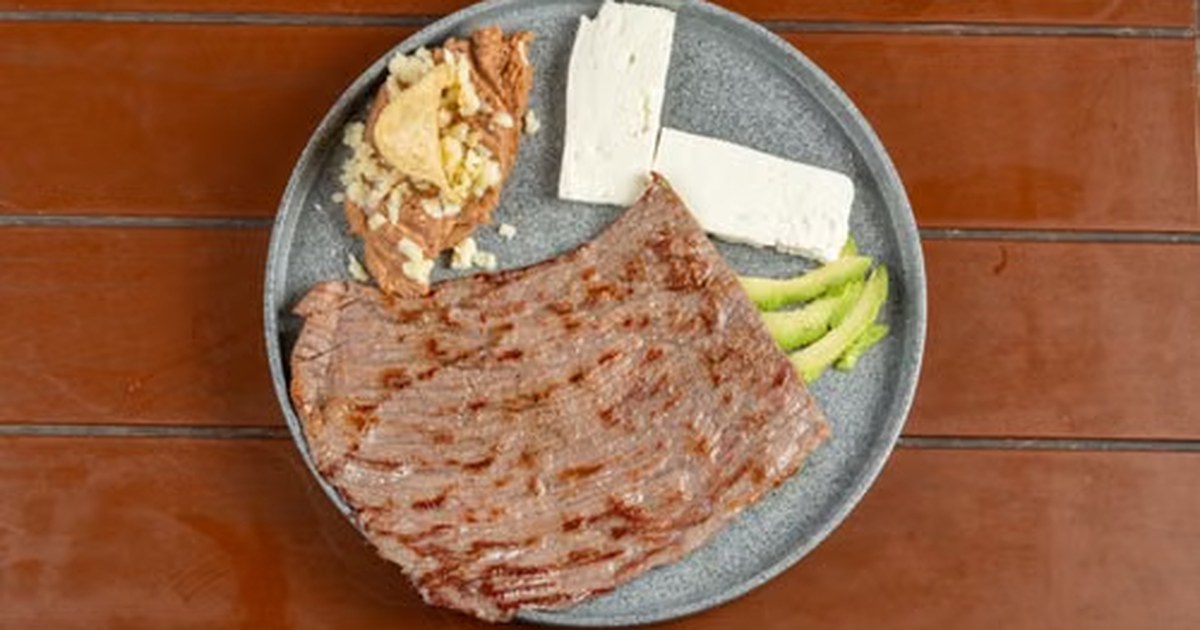 Plato con carne asada, queso fresco, ajo y espárragos, ejemplos de alimentos ricos en proteína.