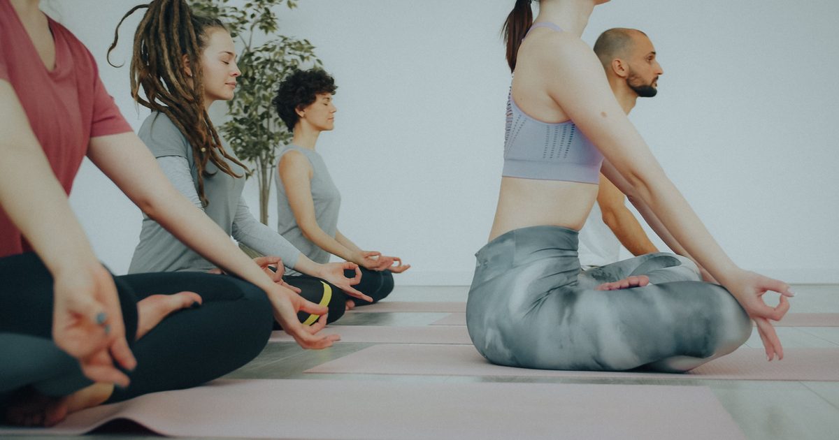 Grupo de personas sentadas en el suelo, meditando con las manos en el regazo.